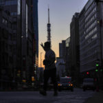 
              A man hails a taxi in Roppingi neighborhood, an entertainment district, in Tokyo Wednesday, Oct. 20, 2021, as Tokyo Tower is silhouetted against the sunrise colored sky in the background. Daily new COVID-19 cases have plummeted from a mid-August peak of nearly 6,000 in Tokyo, with caseloads in the densely populated capital now routinely below 100, an 11-month low. (AP Photo/Kiichiro Sato)
            