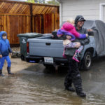 
              From right, Nathan Murray and Ruby Murray, 6, evacuate due to floodwater on Neotomas Avenue in Santa Rosa, Calif., on Sunday, Oct. 24, 2021. (AP Photo/Ethan Swope)
            
