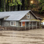 
              Floodwaters from Lake Madrone flow past a house on Oro Quincy Highway on Sunday, Oct. 24, 2021, in Butte County, Calif. The area burned in 2020's North Complex Fire. (AP Photo/Noah Berger)
            