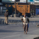 
              An elderly Kashmiri man walks past barbed wire set up as road blockade by soldiers on a road leading towards the site of a gunfight in Pampore, south of Srinagar, Indian controlled Kashmir, Saturday, Oct. 16, 2021. Indian government forces killed five rebels in last 24-hours in disputed Kashmir on Saturday, officials said, as violence increased in recent weeks. (AP Photo/Dar Yasin)
            