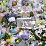 
              A photograph of member of Parliament David Amess is seen among the flower tribute near the Belfairs Methodist Church in Eastwood Road North, where Amess died after he was stabbed several times on Friday, in Leigh-on-Sea, Essex, England, Sunday, Oct. 17, 2021. The slaying Friday of the 69-year-old Conservative lawmaker Amess during his regular weekly meeting with local voters has caused shock and anxiety across Britain's political spectrum, just five years after Labour Party lawmaker Jo Cox was murdered by a far-right extremist in her small-town constituency. (Kirsty O'Connor/PA via AP)
            