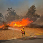 
              In this photo provided by the Santa Barbara County Fire Department, Cal firefighters extinguish a roadside fire off Calle Real near Refugio Rd., in Goleta, Calif., on Tuesday, Oct. 12, 2021.  (Mike Eliason/Santa Barbara County Fire Department via AP)
            