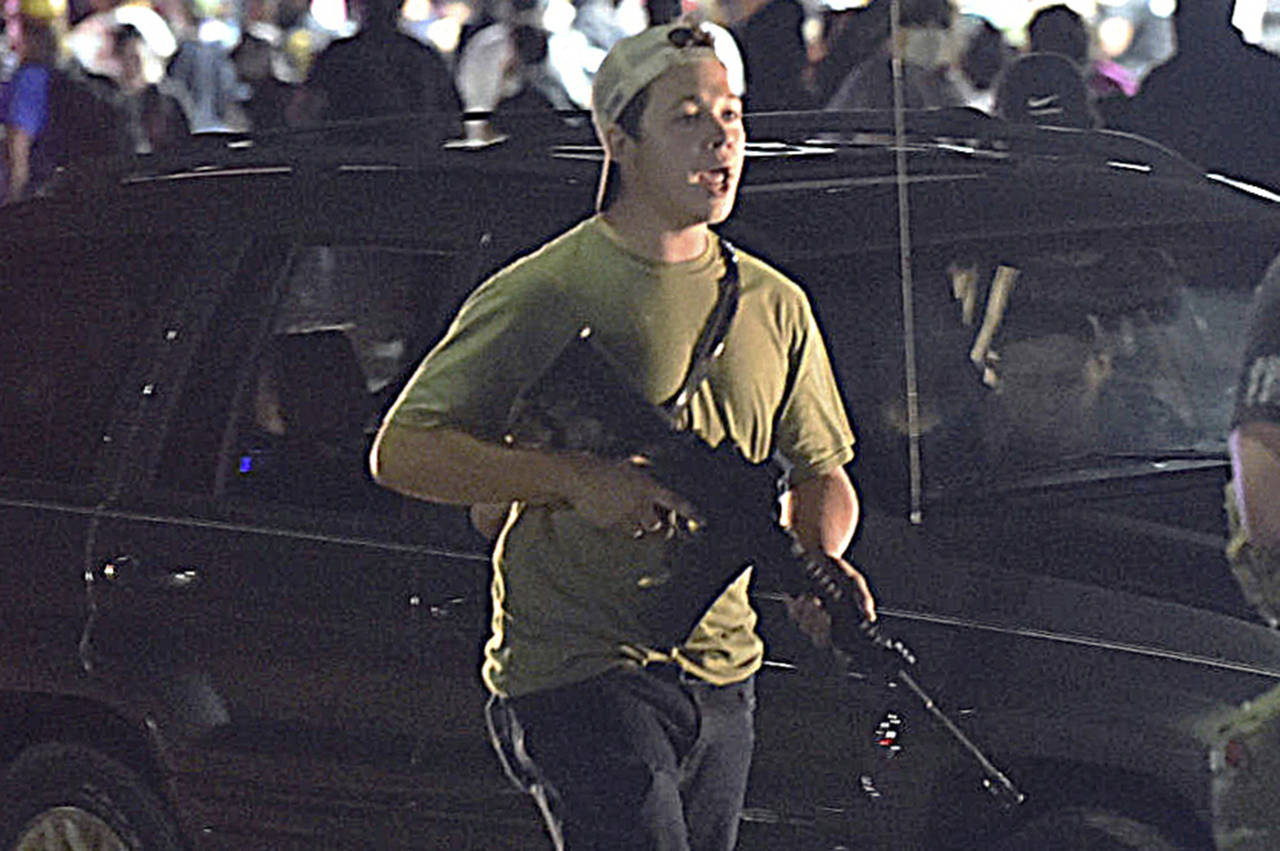 FILE - In this Aug. 25, 2020, file photo, Kyle Rittenhouse carries a weapon as he walks along Sheri...