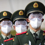 
              Chinese paramilitary police wearing goggles and face masks march in formation at the Yanqing National Sliding Center during an IBSF sanctioned race, a test event for the 2022 Winter Olympics, in Beijing, Monday, Oct. 25, 2021. A northwestern Chinese province heavily dependent on tourism closed all tourist sites Monday after finding new COVID-19 cases. The spread of the delta variant by travelers and tour groups is of particular concern ahead of the Winter Olympics in Beijing in February. Overseas spectators already are banned, and participants will have to stay in a bubble separating them from people outside. (AP Photo/Mark Schiefelbein)
            