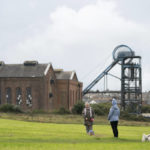 
              Members of the public walks their dogs by the former pithead at Haig Colliery Mining Museum close to the site of a proposed new coal mine near the Cumbrian town of Whitehaven in north-west England, Monday, Oct. 4, 2021. A proposal to dig a new coal mine here is dividing the British government just as it prepares to host a major climate conference. West Cumbria Mining wants to build Britain's first deep coal mine in three decades to extract coking coal, which is used to make steel. The coal would be processed in Whitehaven, 340 miles (550 kilometers) northwest of London. But environmentalists are horrified by the idea. (AP Photo/Jon Super)
            