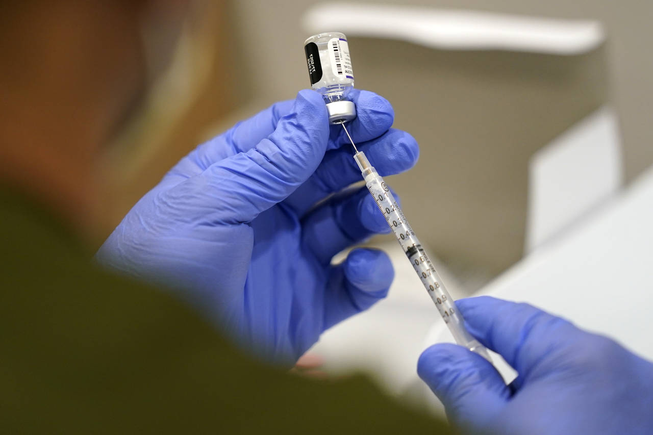 FILE - In this Oct. 5, 2021, file photo a healthcare worker fills a syringe with the Pfizer COVID-1...