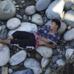 
              A man who is part of a migrant caravan, sleeps on a bed of rocks on the banks of the in Huixtla River, Chiapas state, Mexico, Tuesday, Oct. 26, 2021, on a day of rest before continuing their trek across southern Mexico to the U.S. border. Mexico’s strategy had been to contain migrants in the south, far from the U.S. border while allowing them to apply for asylum in Mexico. (AP Photo/Marco Ugarte)
            