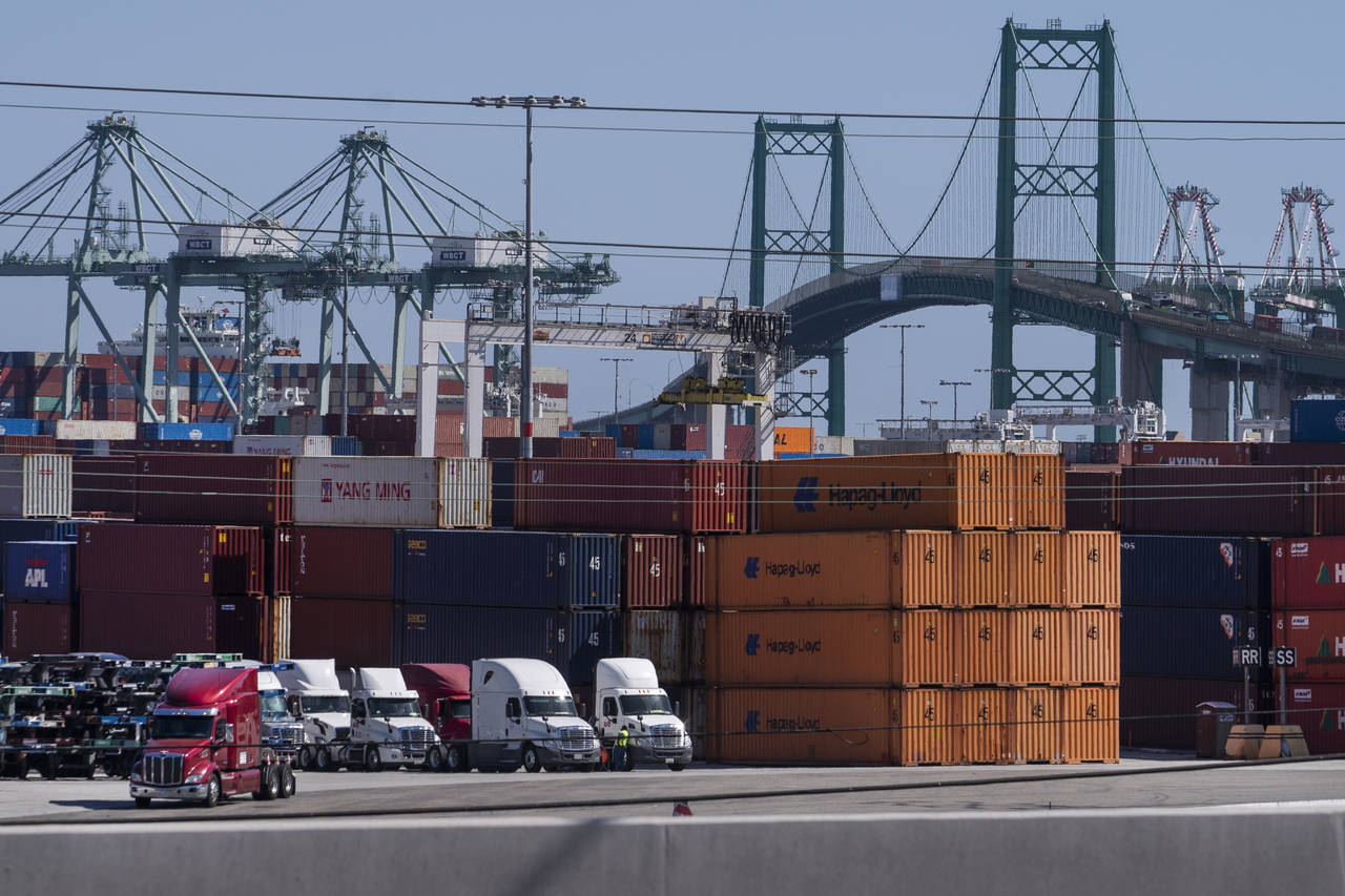 In this Tuesday, Oct. 19, 2021, photo trucks line up next to containers at the Port of Los Angeles ...