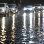 
              Commuters cautiously drive around a flooded section of Peach Avenue on Monday, Oct. 25, 2021, in Clovis, Calif. A massive storm barreled toward Southern California on Monday after flooding highways, toppling trees, cutting power to about 380,000 utility customers and causing rock slides and mud flows in areas burned bare by wildfires across the northern half of the state. (John Walker/Fresno Bee via AP)
            