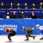 
              Race officials wearing face masks to protect against COVID-19 watch as skaters compete in a preliminary for men's 1000m at the ISU World Cup Short Track speed skating competition, a test event for the 2022 Winter Olympics, at the Capital Indoor Stadium in Beijing, Friday, Oct. 22, 2021. (AP Photo/Mark Schiefelbein)
            