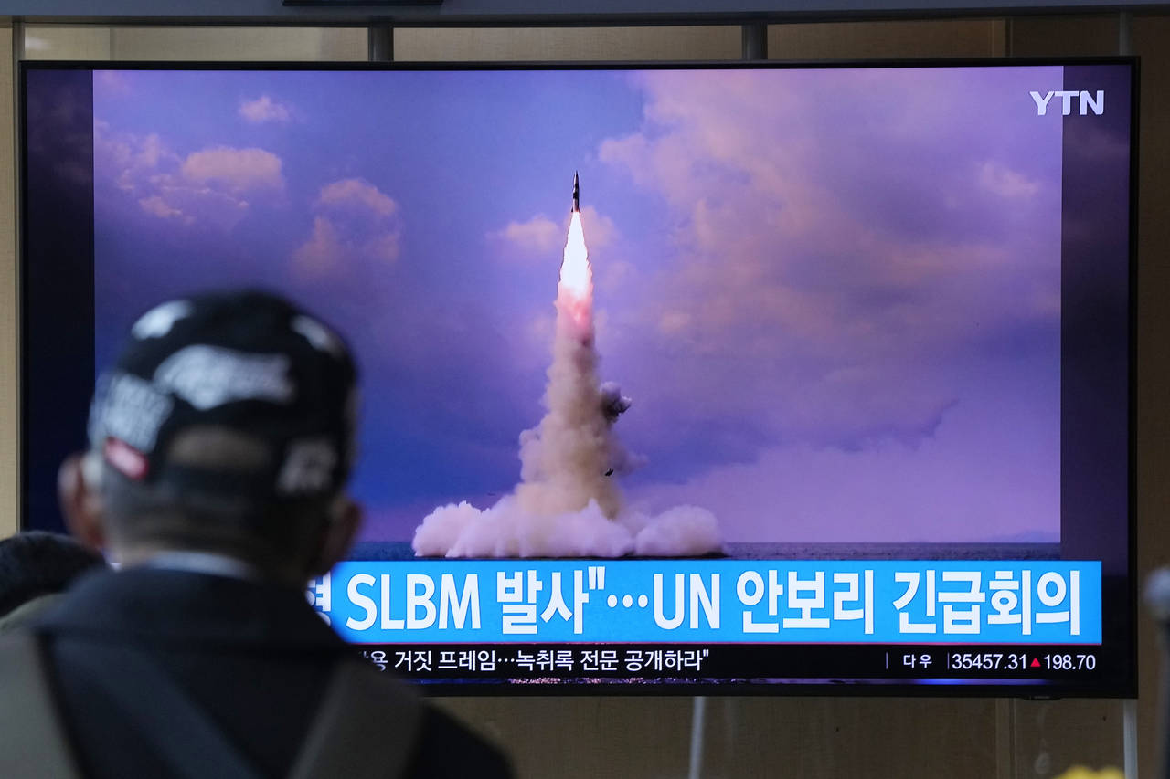 A man watches a TV screen showing an image of North Korea's ballistic missile launched from a subma...