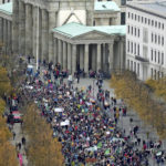 
              People walk past the Brandenburg Gate as they take part in a 'Fridays For Future' climate protest rally in Berlin, Germany, Friday, Oct. 22, 2021. (AP Photo/Michael Sohn)
            
