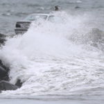 
              A car making its way across the Gooseberry Island causeway, Tuesday, Oct. 26, 2021, in Westport, Mass., is covered by a large wave, as a nor'easter makes its way across the northeast. (Peter Pereira/The Standard-Times via AP)
            