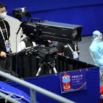 
              A cameraman wearing a face mask to protect against COVID-19 films near a sign reminding attendees to wear masks at the ISU World Cup Short Track speed skating competition, a test event for the 2022 Winter Olympics, at the Capital Indoor Stadium in Beijing, Friday, Oct. 22, 2021. (AP Photo/Mark Schiefelbein)
            