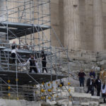 
              Security staff try to take a banner from protesters on scaffolding at the Acropolis hill, in Athens, Greece, Sunday, Oct. 17, 2021. Three people attempted to hang a banner from the Acropolis in Athens Sunday morning in protest at the upcoming Beijing Winter Olympics but were arrested before completing their mission. (AP Photo/Yorgos Karahalis)
            