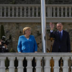 
              Turkish President Recep Tayyip Erdogan, flanked by German Chancellor Angela Merkel, left, waves to the media on the occasion of their meeting at Huber Villa presidential palace, in Istanbul, Turkey, Saturday, Oct. 16, 2021. (AP Photo/Francisco Seco)
            