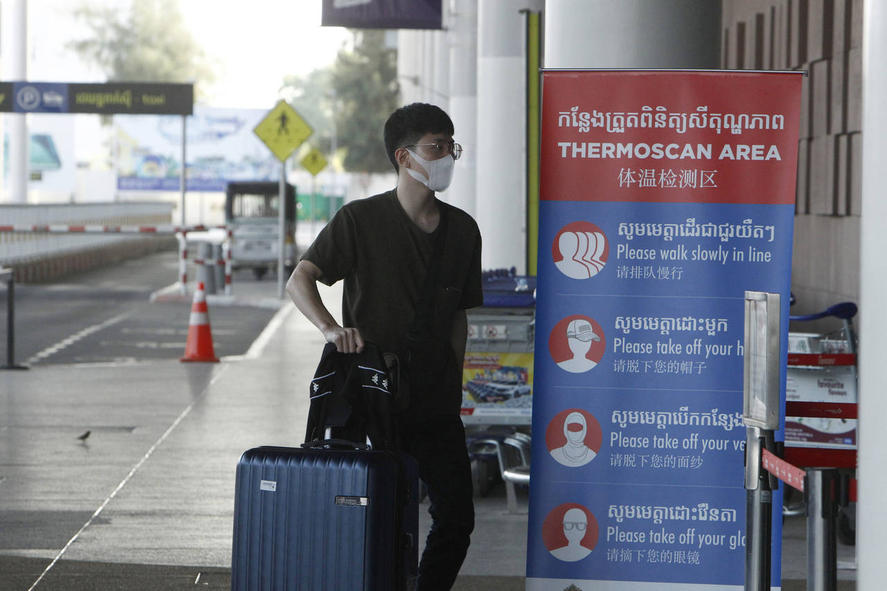 FILE - In this April 3, 2020, file photo, a tourist wearing a face mask enters an area of thermo sc...