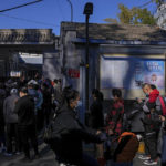 
              Residents wearing face masks to help curb the spread of the coronavirus line up to receive booster shots against COVID-19 at a vaccination site with a billboard displaying a propaganda poster supporting the Beijing 2022 Winter Olympic Games, near a residential area in Beijing, Friday, Oct. 22, 2021. China's capital Beijing has begun offering booster shots against COVID-19, four months before the city and surrounding regions are to host the Winter Olympics. (AP Photo/Andy Wong)
            