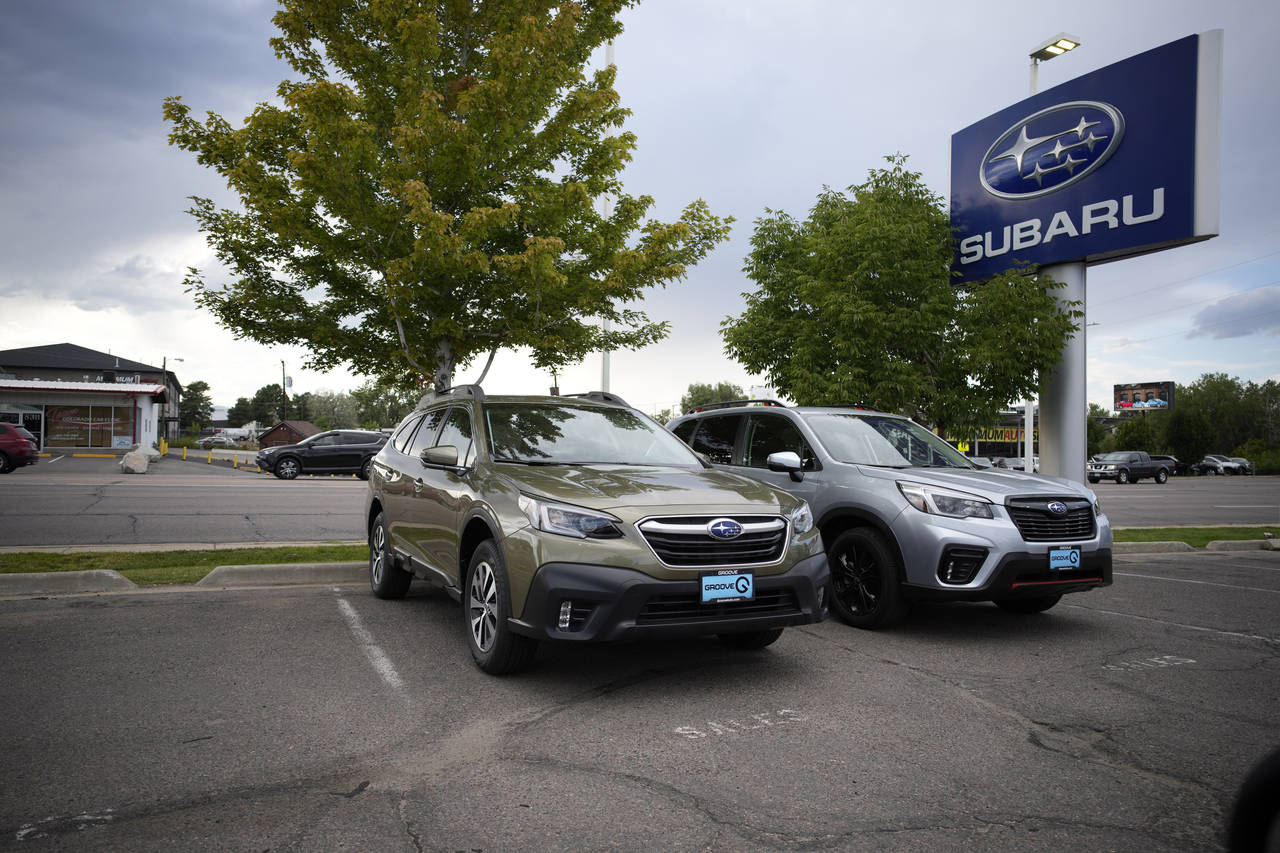 FILE - A pair of unsold 2021 sports-utility vehicles—Outback at left, Forester on right— sit in...