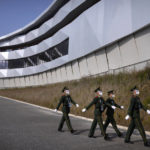
              Chinese paramilitary police wearing goggles and face masks march in formation at the Yanqing National Sliding Center during an IBSF sanctioned race, a test event for the 2022 Winter Olympics, in Beijing, Monday, Oct. 25, 2021. A northwestern Chinese province heavily dependent on tourism closed all tourist sites Monday after finding new COVID-19 cases. The spread of the delta variant by travelers and tour groups is of particular concern ahead of the Winter Olympics in Beijing in February. Overseas spectators already are banned, and participants will have to stay in a bubble separating them from people outside. (AP Photo/Mark Schiefelbein)
            