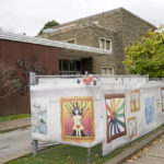 
              This photo from Oct. 16, 2021, shows the dormant landmark Tree of Life synagogue as a man jogs past the fencing with artwork submitted by Pittsburgh area school students in Pittsburgh's Squirrel Hill neighborhood. Renowned architect Daniel Libeskind is among those working to transform the site to share space with the Holocaust Center of Pittsburgh. The goal to create a solemn memorial as well as a place of regular activity is underway as the date marking the third year since 11 people were killed in America's deadliest antisemitic attack on Oct. 27, 2018 approaches. (AP Photo/Keith Srakocic)
            