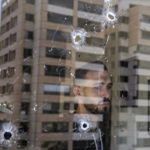 
              An employee looks through an office window riddled with bullet holes after the deadly clashes that erupted last Thursday along a former 1975-90 civil war front-line between Muslim Shiite and Christian areas, in Ain el-Rumaneh neighborhood, Beirut, Lebanon, Tuesday, Oct. 19, 2021. The shootout on the streets of Beirut between rival Christian and Muslim groups has revived memories of the country's 1975-90 civil war and fired up sectarian passions in a country that never dealt with the causes of its violent past. (AP Photo/Hassan Ammar)
            