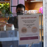 
              A sign explaining the LA County Mandate is posted for customers inside the Intelligentsia Coffee on Sunset Blvd., in Los Angeles, Monday, Nov. 29, 2021. Enforcement began Monday in Los Angeles for one of the strictest vaccine mandates in the country, a sweeping measure that requires proof of COVID-19 shots for everyone entering a wide variety of businesses from restaurants to theaters and gyms to nail and hair salons. (AP Photo/Damian Dovarganes)
            