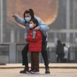 
              A woman and a child, both wearing face masks to protect from COVID-19 look at a commercial office building in Beijing, Sunday, Nov. 28, 2021. (AP Photo/Andy Wong)
            