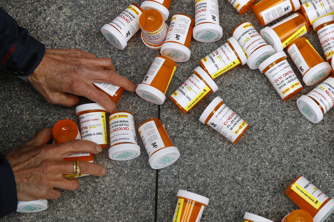 FILE - A protester gathers containers that look like OxyContin bottles at an anti-opioid demonstrat...