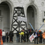 
              FILE - In this Feb. 6, 2015, file photo, protesters prepare to take down a makeshift oil derrick that was set up in front of the California State Office Building to protest fracking in San Francisco. California regulators are citing climate change for the first time as they deny new permits for hydraulic fracturing, a process used to extract oil and gas from the ground. In denying 50 fracking permits this year, the state's oil and gas supervisor said he was using his discretion to protect public health, safety and environmental quality and to mitigate greenhouse gas emissions. (AP Photo/Jeff Chiu, File)
            
