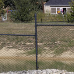 
              A staff member at the Mother's Heart Learning Center, in background, opens a door to let children inside from the center's playground in Arlington, Texas, on Monday, Oct. 25, 2021. The fracking pond in the foreground is part of a natural gas drill site, known as "AC-360," a few hundred feet from the daycare. The site is operated by TEP Barnett, a subsidiary of French energy giant Total Energies. It is one of Total's 33 well sites in Arlington containing 163 natural gas wells, most of them tucked in urban neighborhoods in Arlington. (AP Photo/Martha Irvine)
            