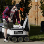 
              Food is loaded into a robot at the Bowling Green State University campus in Bowling Green, Ohio on Thursday, Oct. 13, 2021. Robot food delivery is no longer the stuff of science fiction. Hundreds of little robots __ knee-high and able to hold around four large pizzas __ are now navigating college campuses and even some city sidewalks in the U.S., the U.K. and elsewhere. While robots were being tested in limited numbers before the coronavirus hit, the companies building them say pandemic-related labor shortages and a growing preference for contactless delivery have accelerated their deployment. (AP Photo/Carlos Osorio)
            
