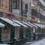 
              Christmas booths are all closed on the Christmas market in Innsbruck, Austria, as snow falls on Sunday, Nov. 28, 2021. Austria is in a lockdown following a spike in COVID-19 infections. (AP Photo/Michael Probst)
            