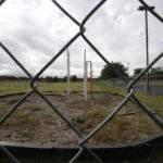 
              A fence surrounds an abandoned playground near a natural gas well site in Arlington, Texas, on Sunday, Oct. 24, 2021. The playground at the Cornerstone Baptist Church and school was closed because it is about 400 feet from wells at the site, which is now operated by TEP Barnett, a subsidiary of French energy giant Total Energies. Church leaders signed a deal with the original well site owners to use the land for drilling and say they have received a "substantial" amount of royalties. A new playground was built about 200 feet to the north of this one, putting it just beyond the 600 feet minimum required by the city of Arlington. (AP Photo/Martha Irvine)
            