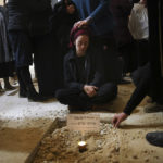 
              Atiya, wife of Yehuda Dimentman, who was killed in a Palestinian shooting attack, mourns next to his grave, during his funeral in Givat Shaul cemetery in Jerusalem, Friday, Dec. 17, 2021. Palestinian gunman opened fire Thursday night at a car filled with Jewish seminary students next to a West Bank settlement outpost, killing Yehuda Dimentman and lightly wounding two other people, Israeli officials said. (AP Photo/Oren Ziv)
            