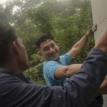 
              A couple of migrants hang on to the back of a truck as they travel north from the community of La Lima in southern Veracruz state, Mexico, Wednesday, Nov. 24, 2021.  The United States and Mexico announced Thursday, Dec. 2, a deal to re-implement under court order a Trump-era policy known as “Remain in Mexico” at Mexico’s northern border that forced asylum seekers to wait out their cases inside Mexico. (AP Photo/Felix Marquez)
            