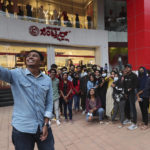 
              A group of young people, many wearing face masks as a precaution against COVID-19, pose for a selfie outside a shopping mall in Bengaluru, capital of the southern Indian state  of Karnataka, Thursday, Dec. 2, 2021. India on Thursday confirmed its first cases of the omicron coronavirus variant in two men in Karnataka who came from abroad. (AP Photo/Aijaz Rahi)
            