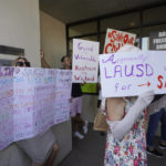 
              FILE - Anti-vaccine mandate protesters hold signs outside the front doors of the Los Angeles Unified School District, LAUSD headquarters in Los Angeles, on Sept. 9, 2021. New research indicates that far-right extremists and white supremacists are gaining new followers and new influence by co-opting conspiracy theories about COVID-19. (AP Photo/Damian Dovarganes, File)
            