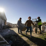 
              Volunteers, most of whom are employees of the Mayfield Consumer Products factory, help salvage possessions from the destroyed home of Martha Thomas, who survived the tornado by hiding in the bathroom, in the aftermath of tornadoes that tore through the region, in Mayfield, Ky., Monday, Dec. 13, 2021. (AP Photo/Gerald Herbert)
            