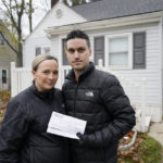 
              Nicole and Simon Obarto, holding a lead and copper analysis of water from the Oakland County Health Division, stand outside their home in Royal Oak, Mich., on  Thursday, Nov. 18, 2021. The couple had their water line tested for lead and the results were high enough to have the lead service line replaced. (AP Photo/Carlos Osorio)
            