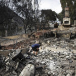 
              FILE - In this Nov. 13, 2018, file photo, Roger Kelton searches through the remains of his mother-in-law's home leveled by the Woolsey fire, in the southern California city of Agoura Hills. Southern California Edison has reached an agreement with state regulators on Thursday, Dec. 16 2021, for more than half a billion dollars in penalties related to five wildfires, including the Woolsey fire. (AP Photo/Jae C. Hong, File)
            
