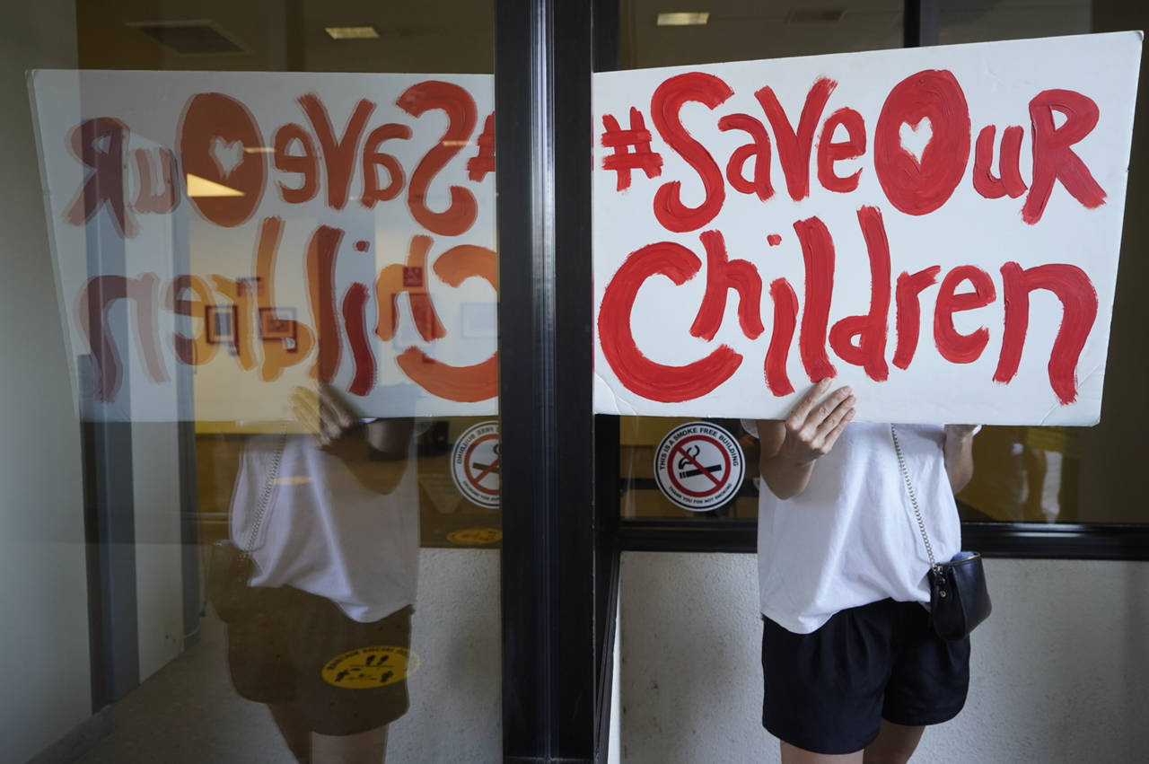 FILE - An anti-vaccine mandate protester holds a sign outside the front windows of the Los Angeles ...