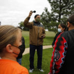 
              Lakota culture teacher Jason Drapeaux, Jr .gathers students at an assembly for Orange Shirt Day on Sept. 30, 2021, in Pine Ridge, S.D. Students and teachers wore orange in solidarity with Indigenous children of past generations who suffered cultural loss, family separation and sometimes abuse and neglect while compelled to attend hundreds of residential schools that once dotted the map across the United States and Canada from the late 19th to the mid-20th centuries. (AP Photo/Emily Leshner)
            