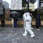 
              A medical workers passes by people as they wait for the coronavirus testing outside a public health center in Seoul, South Korea, Wednesday, Dec. 15, 2021. Halting its steps toward normalcy, South Korea will clamp down on social gatherings and cut the hours of some businesses to fight a record-breaking surge of the coronavirus that has led to a spike in hospitalizations and deaths. (AP Photo/Ahn Young-joon).
            