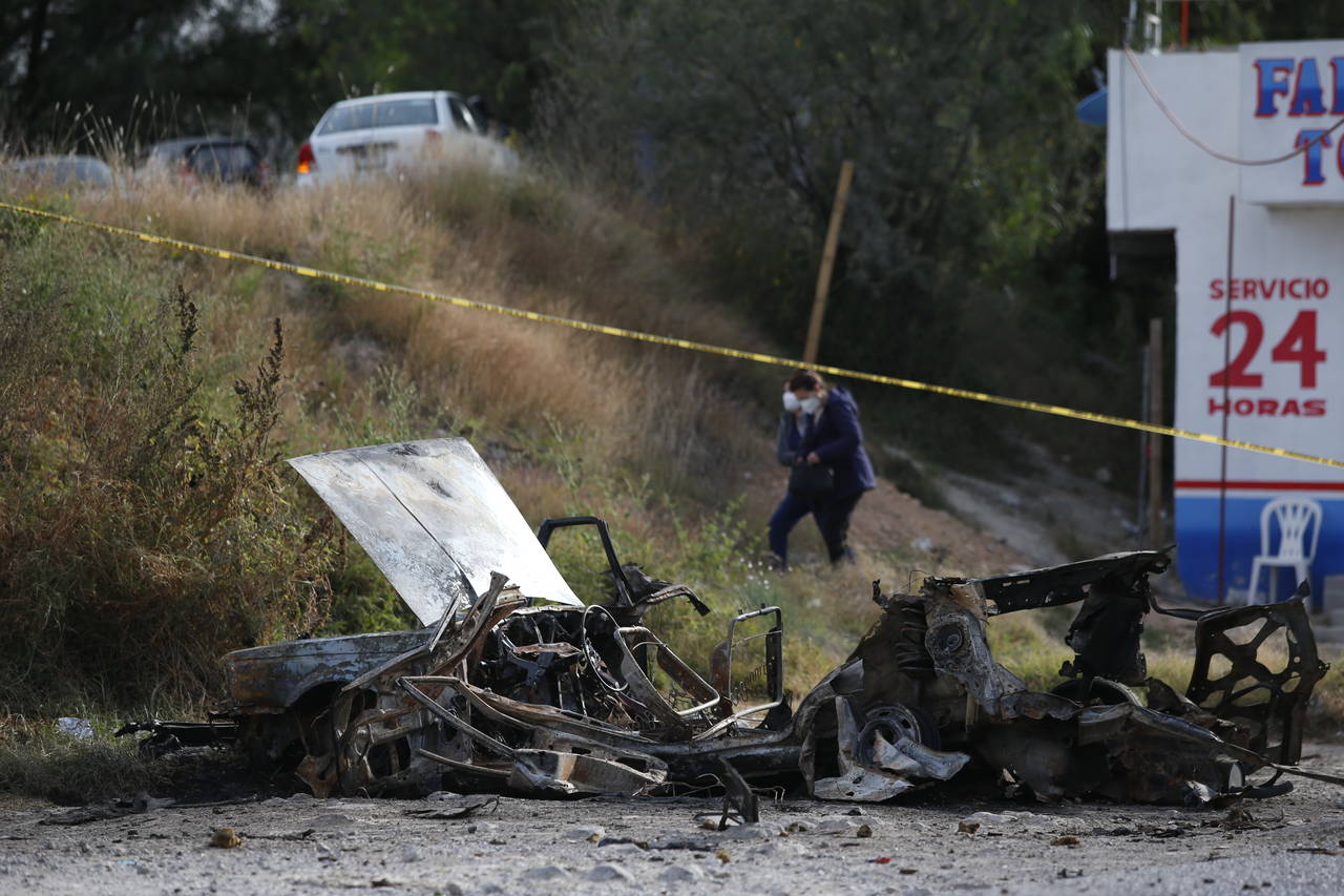 Locals walk past a burned-out car outside the Tula General Hospital, after a gang rammed several ve...