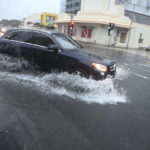 
              A car turns onto a flooded Cooke Street, Monday, Dec. 6, 2021, in Honolulu. A strong storm packing high winds and extremely heavy rain has flooded roads and downed power lines and tree branches across Hawaii. (AP Photo/Marco Garcia)
            