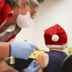 
              A boy wearing a Christmas hat is vaccinated with the Biontech/Pfizer vaccine at a vaccination campaign in the shopping centre "Stadtzentrum Schenefeld" near Hamburg in Schnenefeld, Germany, Tuesday, Dec. 14, 2021. In Schleswig-Holstein, Corona vaccination campaigns for children aged five to eleven began on Tuesday. (Christian Charisius/dpa via AP)
            