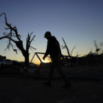 
              A cleanup worker walks past damaged trees and debris at the end of the day Sunday, Dec. 12, 2021, in Mayfield, Ky. Tornadoes and severe weather caused catastrophic damage across several states Friday, killing multiple people. (AP Photo/Mark Humphrey)
            