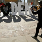 
              Brad Dezek takes a photo of his wife, Becky Dezek, at a Christmas market in downtown Denver on Friday, Dec. 3, 2021. The couple flew in from snowy Waukesha, Wisc., to find unseasonably mild weather in Denver. The Mile High City has already shattered its 87-year-old record for the latest measurable snowfall set on Nov. 21, 1934, and it's a little more than a week away from breaking an 1887 record of 235 consecutive days without snow. (AP Photo/Thomas Peipert)
            