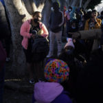 
              FILE - A woman seeking asylum in the United States waits with others for news of policy changes on Feb. 19, 2021, in Tijuana, Mexico. The Biden administration is set to reinstate a Trump-era policy to make asylum-seekers wait in Mexico for hearings in U.S. immigration court this week with changes and additions. A U.S. official says the first migrants are to be sent from El Paso, Texas, back to Ciudad Juarez. Timing was in flux as officials made final preparations but it may begin Tuesday, Dec. 7, 2021. (AP Photo/Gregory Bull, File)
            